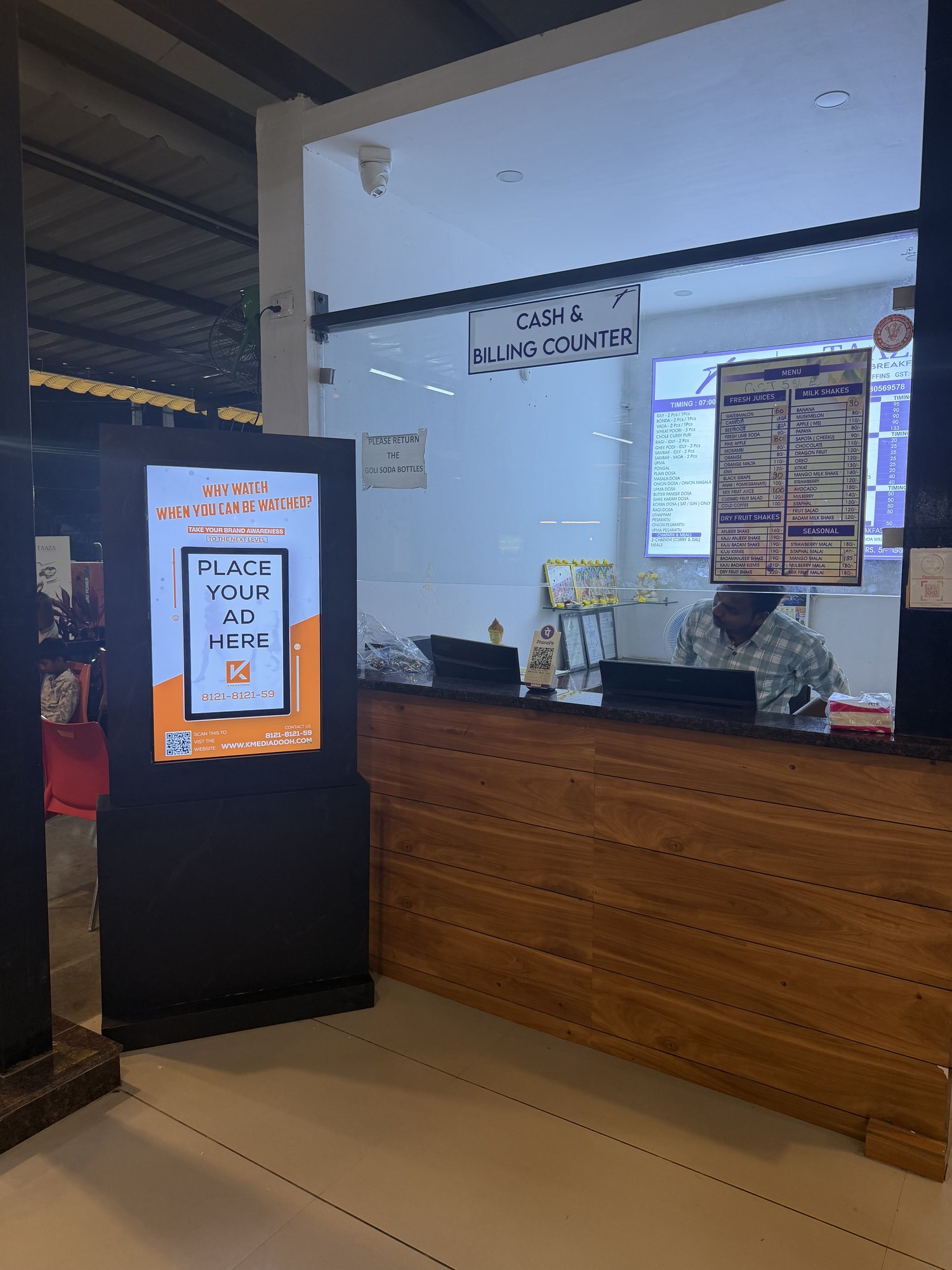 KMEDIA digital standee beside a restaurant cash and billing counter
