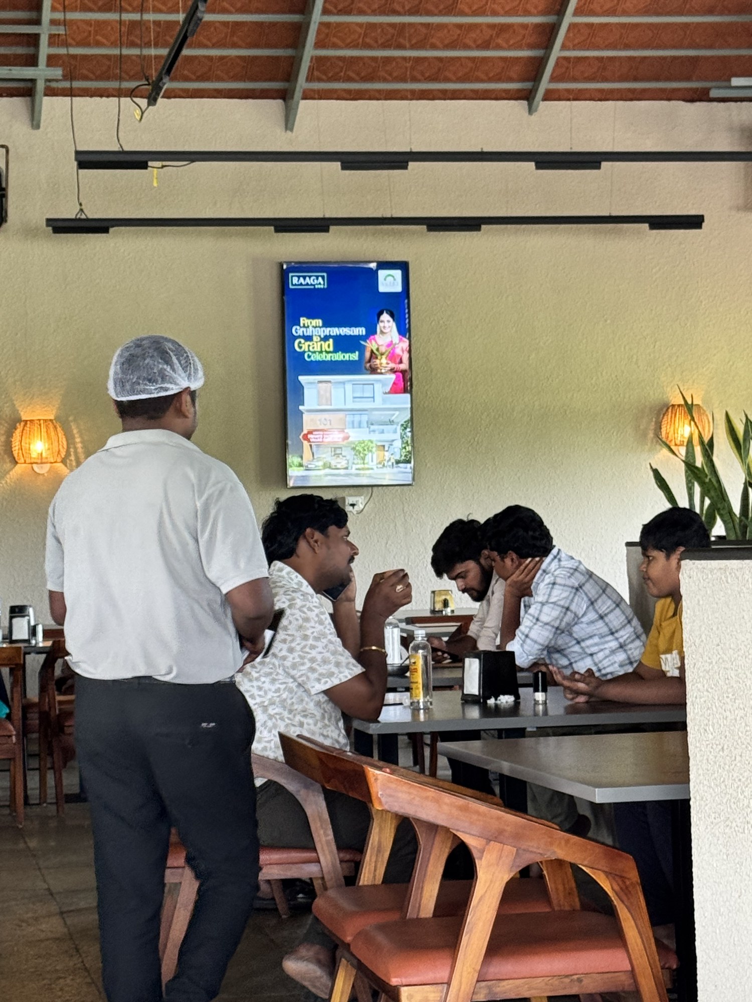 Raaga villas advertisement on KMEDIA screen in a restaurant dining hall